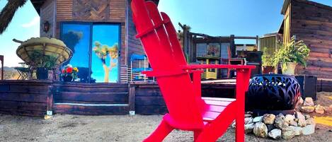 Une chaise rouge est placée devant un bâtiment dont la façade est en bois et qui possède une grande fenêtre.