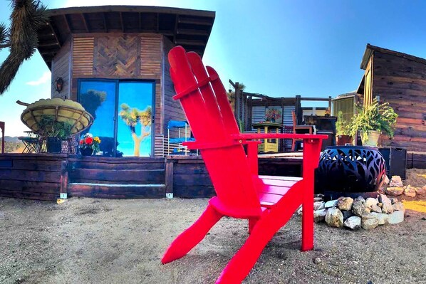 Une chaise rouge est placée devant un bâtiment dont la façade est en bois et qui possède une grande fenêtre.