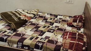 Een enkel bed met een gewatteerde spreideken en een kussen.
