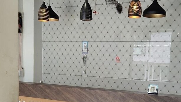 Een receptie met een behang met patroon, een houten receptiebalie en hanglampen.