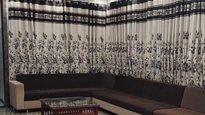 Een moderne woonkamer met een hoekbank, een glazen salontafel en behang met patroon.