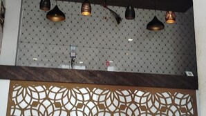 Een receptiegedeelte met een patroonwand, plafondverlichting en een houten balk.