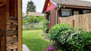A wooden house with a stone staircase, a fenced yard, and a garden with various plants. - Apartment 'Belchenwind Type A, 45sqm' (Münstertal)