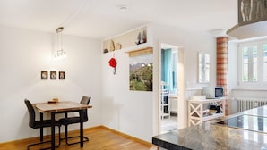 A kitchen with a wooden table and chairs, a microwave, and a view of the outdoors. - Apartment 'Belchenwind Type A, 45sqm' (Münstertal)