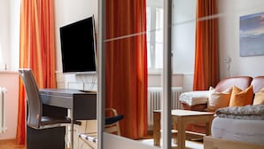 A modern room with a desk, chair, television, and a sofa. - Apartment 'Belchenwind Type A, 45sqm' (Münstertal)