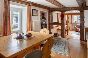 A wooden dining table with chairs, a bookshelf, and a radiator. - Apartment 'Belchenwind Typ B, 65sqm, Terrace' with Mountain View, Private Terrace & Wi-Fi (Münstertal)