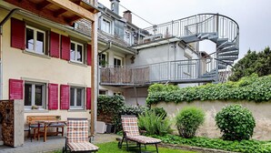 A two-story building with a spiral staircase, outdoor seating, and a garden. - Apartment 'Belchenwind Typ B, 65sqm, Terrace' with Mountain View, Private Terrace & Wi-Fi (Münstertal)