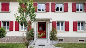 A building with red shutters, a white facade, and a number '29' sign. - Apartment 'Belchenwind Typ B, 65sqm, Terrace' with Mountain View, Private Terrace & Wi-Fi (Münstertal)