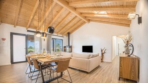 Ein geräumiger Essbereich mit Holztisch, gedeckt für eine Mahlzeit, einer Couch und einem Fernseher in einem modernen Wohnzimmer.