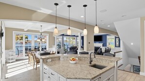 A spacious kitchen with a large island, pendant lighting, and a view of the outdoors.