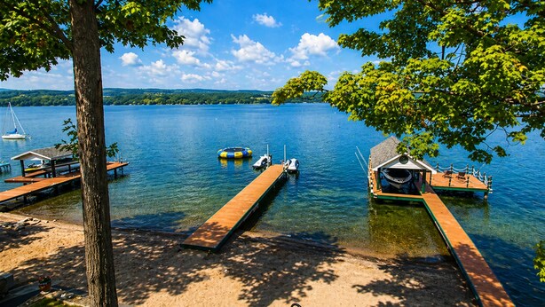 A lakeside dock with boats, a wooden pier, and a tree.