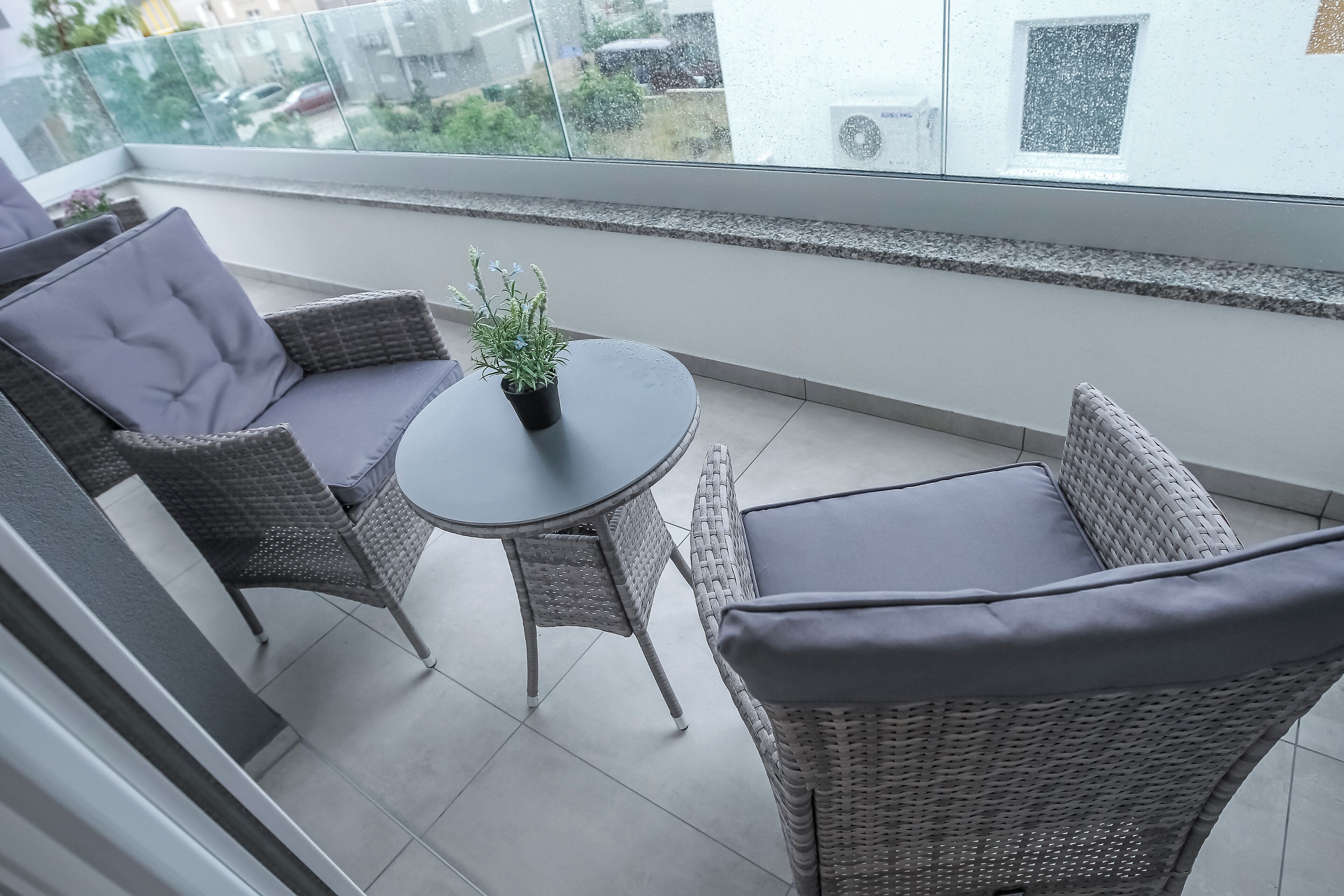 Un balcone con mobili in vimini, un tavolino e una pianta in vaso.