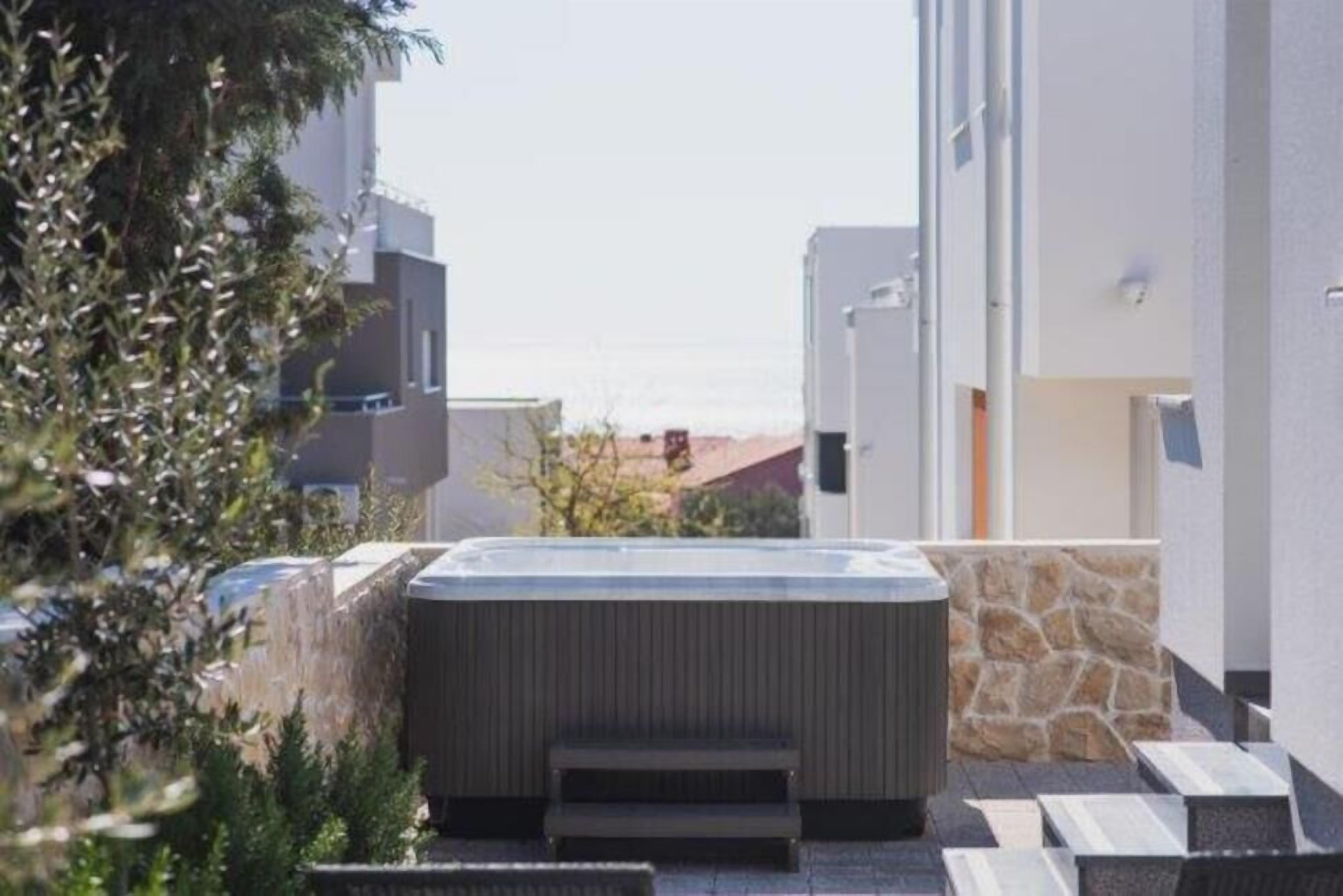 A modern building with a hot tub in the courtyard, surrounded by stone walls and greenery.