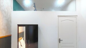 A bedroom with a bed, a wardrobe, a door, and a ceiling light fixture. - Let'stay- NX-One Noida (Greater Noida)