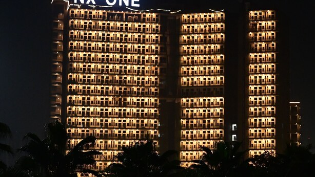 A high-rise building with the sign "NX-ONE" at the top. - Let'stay- NX-One Noida (Greater Noida)