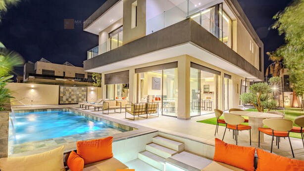 A modern house with a swimming pool, outdoor seating, and a well-lit patio area. - Villa Akenza (Marrakech)