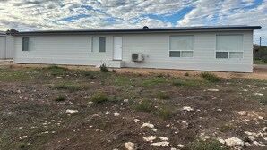 Il s’agit d’une maison mobile de plain-pied, dotée d’un toit plat, de deux fenêtres sur le côté et d’un climatiseur fixé sur le mur extérieur.