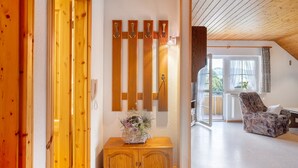 A wooden interior with a wooden cabinet, a chair, and a wall-mounted light fixture. - Holiday Apartment with Mountain View 1 with Balcony and Wi-Fi (Wieden)