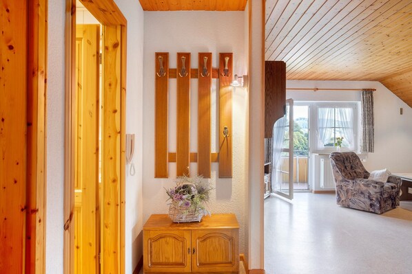 A wooden interior with a wooden cabinet, a chair, and a wall-mounted light fixture.
