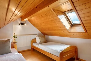 Une petite pièce aux murs lambrissés, avec un lit simple, un puits de lumière et un radiateur.