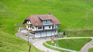 A house with a sloped roof, solar panels, and a winding road. - Holiday Apartment with Mountain View 1 with Balcony and Wi-Fi (Wieden)
