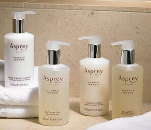 Cuatro botellas de productos Asprey Purple Water sobre una encimera.