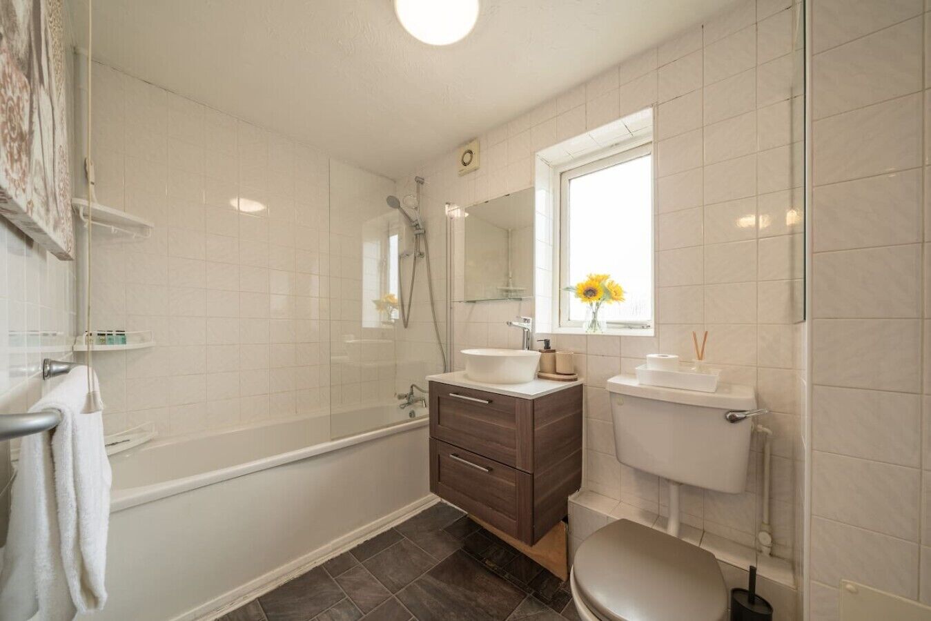 Un baño con bañera, ducha, tocador con lavabo, inodoro y ventana con vistas al exterior.