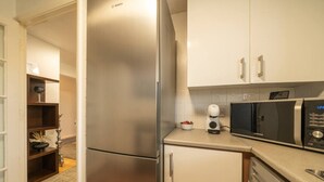 Una cocina compacta con un refrigerador de acero inoxidable, un microondas y una cafetera.