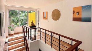 A modern interior with a staircase, a view of greenery outside, and artwork on the walls. - Jungle House Phuket - Seaview Retreat (Patong)