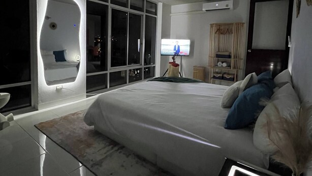 A modern bedroom with a large bed, a TV, and a unique wall feature. - Jungle House Phuket - Seaview Retreat (Patong)