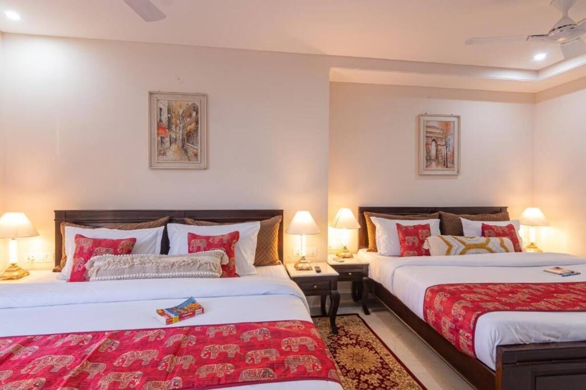 Habitación de hotel con dos camas, cada una con una mesita de noche, lámparas de noche y un cuadro en la pared.