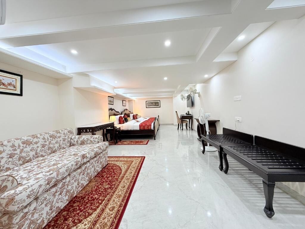 A modern hotel room with a sofa, a bed, a dining table, and a piano.