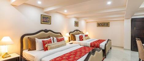 A hotel room with two beds, a nightstand, a chair, and a door.