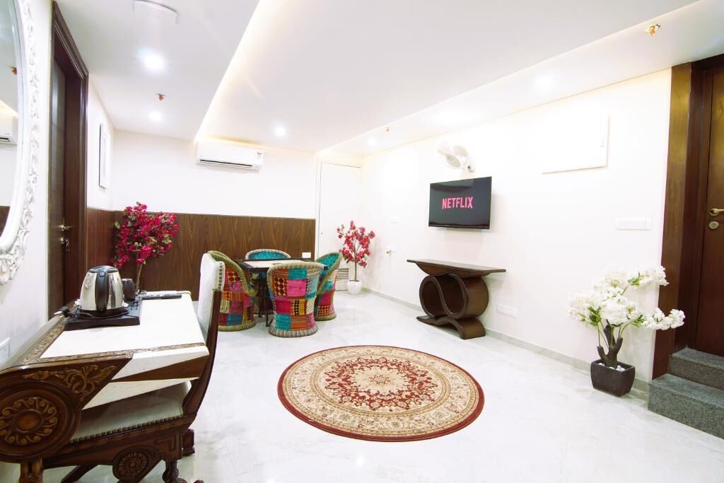 A modern hotel lobby with a dining area, a television, and a staircase.