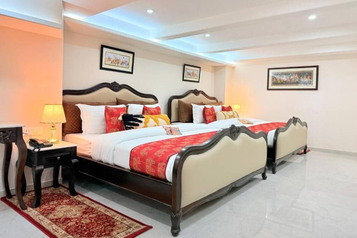 Una cama doble con una colcha rojo y blanco, dos mesitas de noche y una alfombra roja estampada.