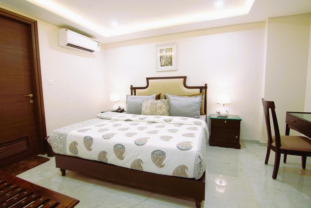 Une chambre à coucher comprenant un lit, des tables de chevet, une chaise et un appareil de climatisation.