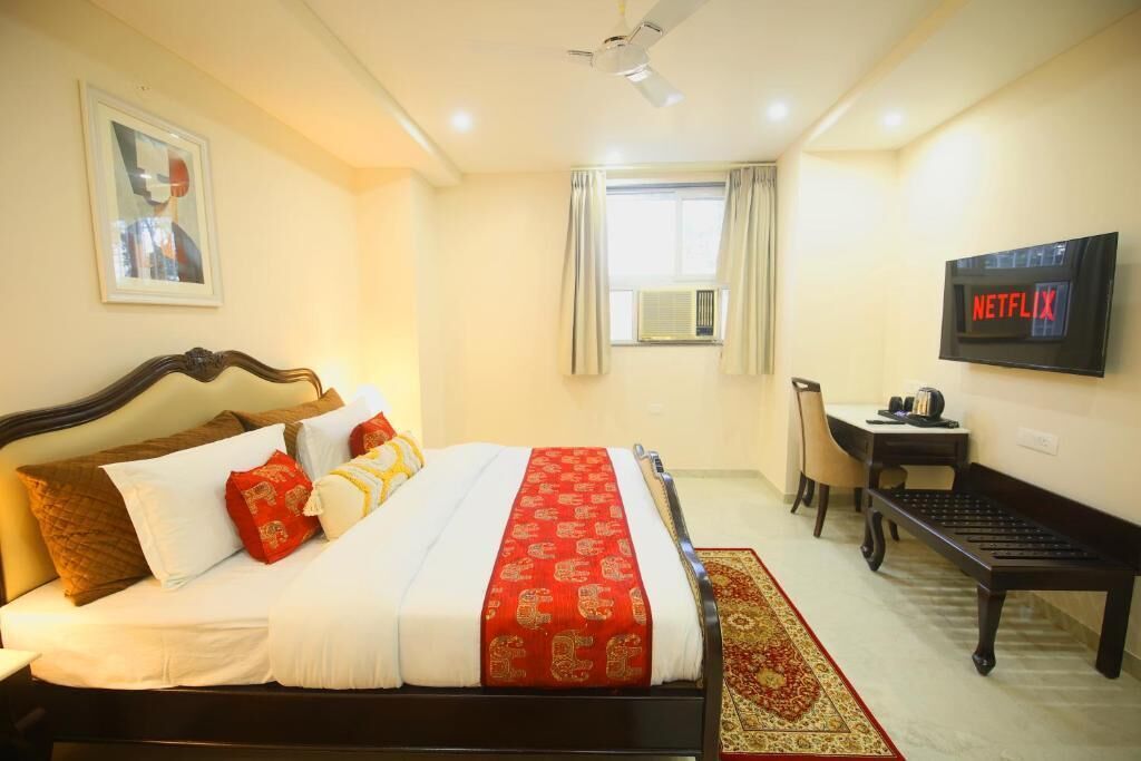 A hotel room with a bed, a desk, a chair, a television, and a window with curtains.