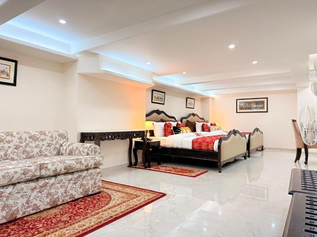 A hotel room with a bed, a sofa, a desk, and a fan.