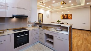 A modern kitchen with a built-in oven, a Bosch range hood, and a marble countertop.
