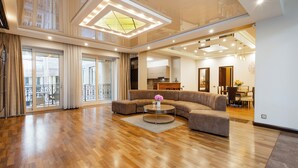 A spacious living room with a large sectional sofa, a round coffee table, and a view of the city through large windows.