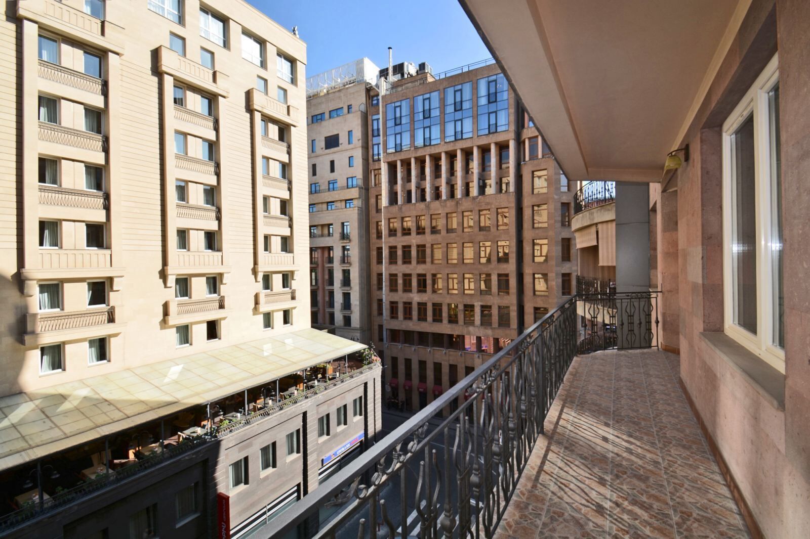 A balcony with a view of adjacent buildings, featuring multiple floors and balconies.