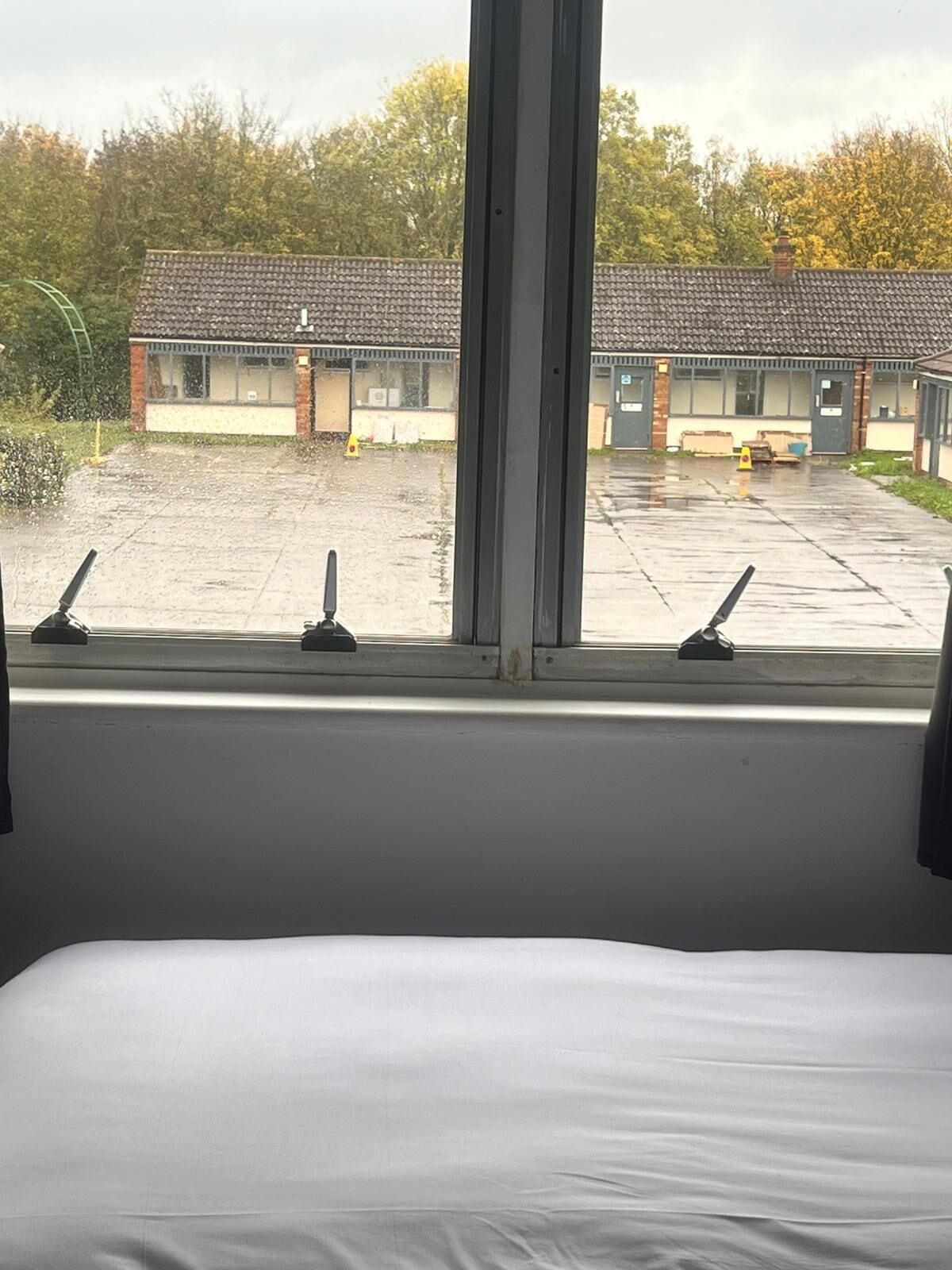 A room with a large window overlooking a building with a tiled roof and a paved area.