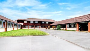 A courtyard with a central building and two wings, featuring a tiled roof and a grassy area. - Rivenhall End Hotel (Witham)