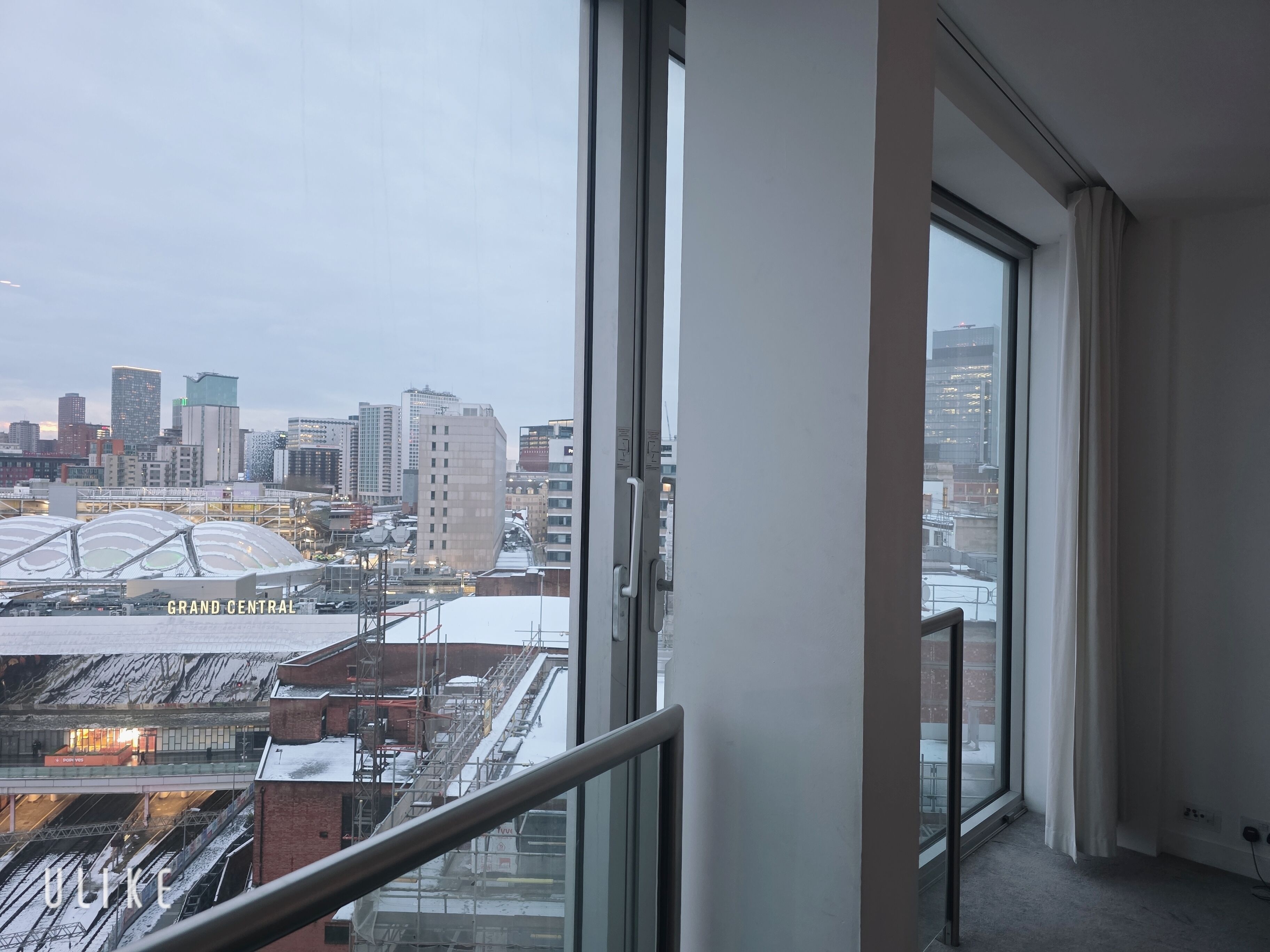 A cityscape view from a high-rise building with large windows, a modern architectural style, and a clear sky.