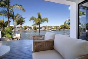 A balcony with wicker furniture, a view of a marina, and palm trees. - Alua by Khove (Helensvale)