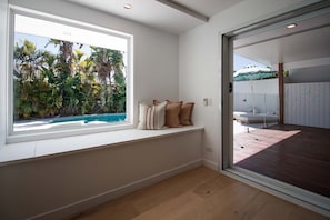 A room with a large window overlooking a pool and lush greenery. - Muse by Khove (Burleigh Waters)