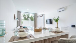 Une cuisine moderne dotée d’un îlot central, de grandes fenêtres et d’un téléviseur à écran plat.