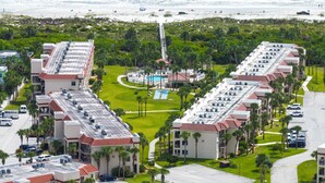 A hotel with a pool, beach view, and parking area.