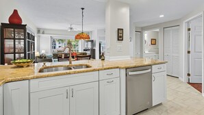 A modern kitchen with white cabinetry, a granite countertop, and stainless steel appliances.