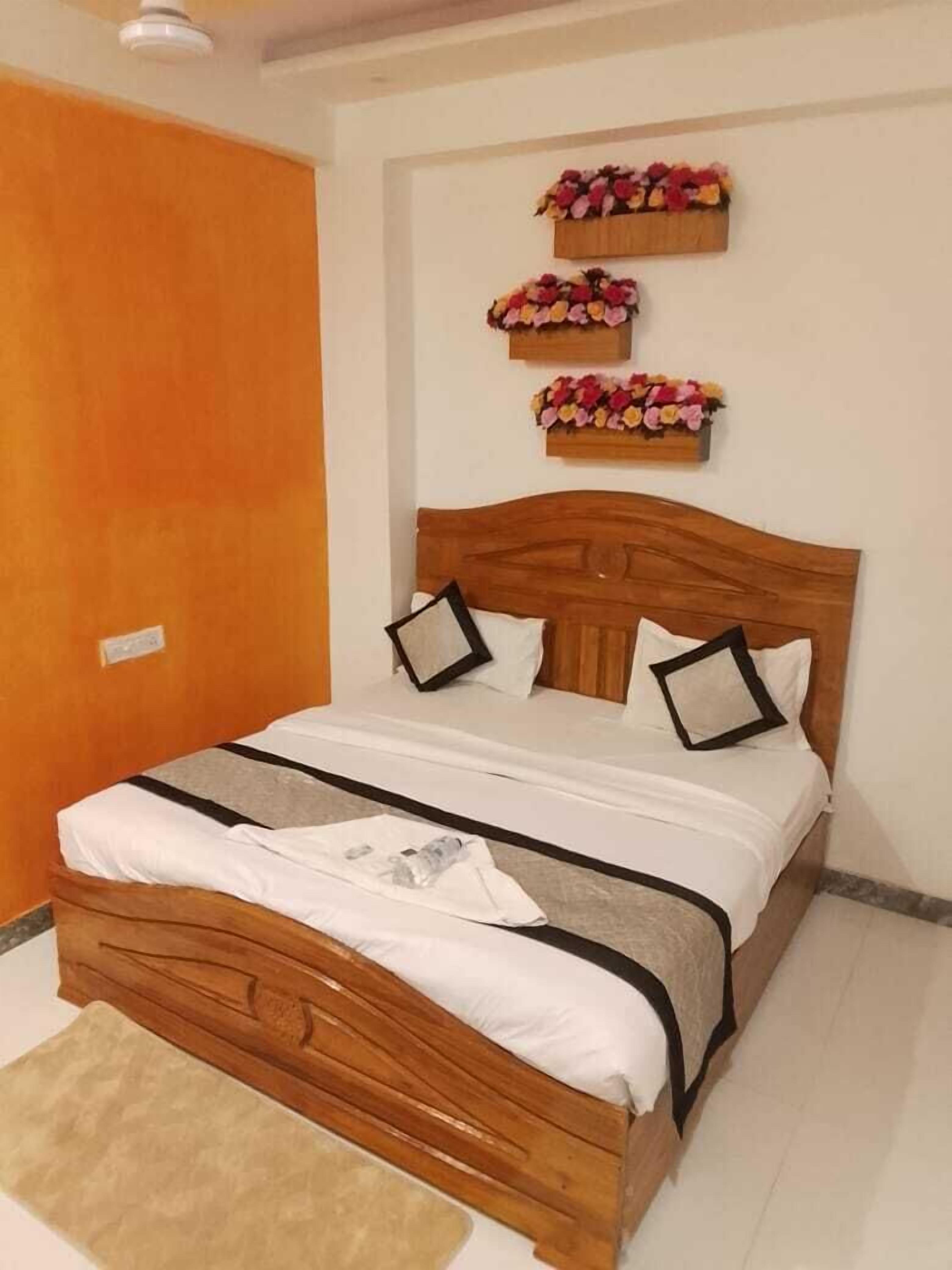 Ein ordentlich bezogenes Bett mit Holz Kopfteil, weißer Bettwäsche und zwei schwarzen Kissen.